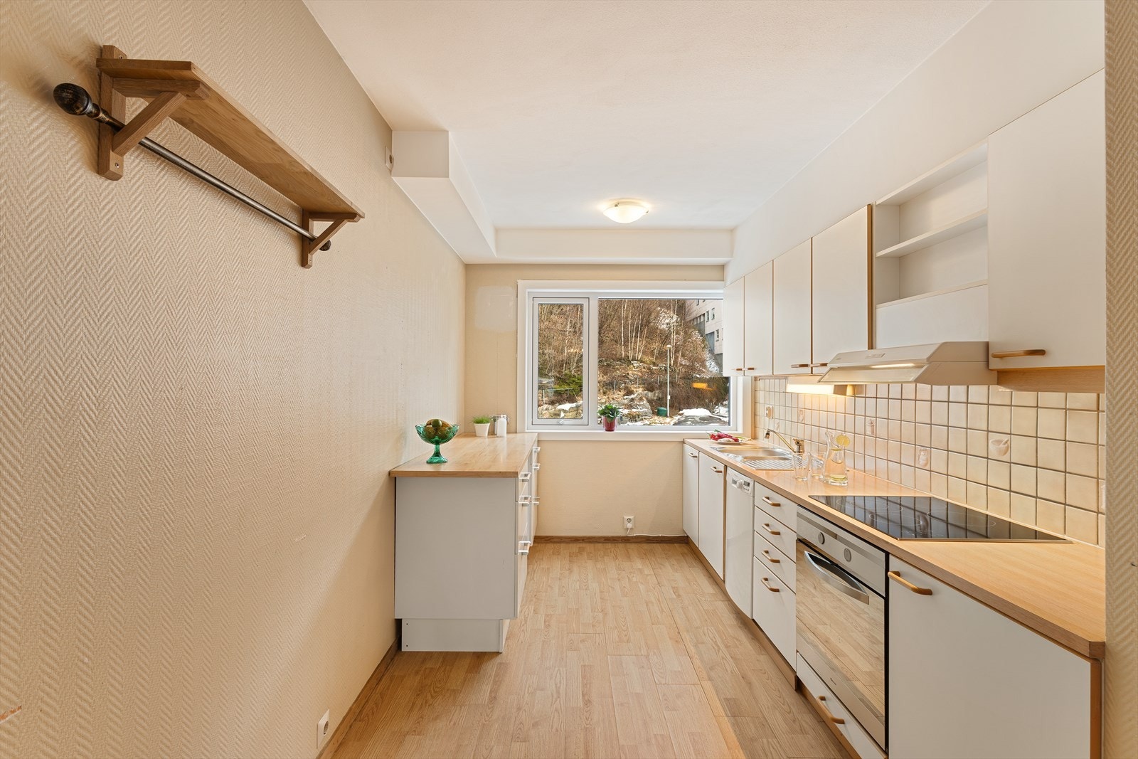 Kjøkkenet har slette fronter og laminat benkeplate. Det er fliser på vegg over benkeplaten. Galleribilde