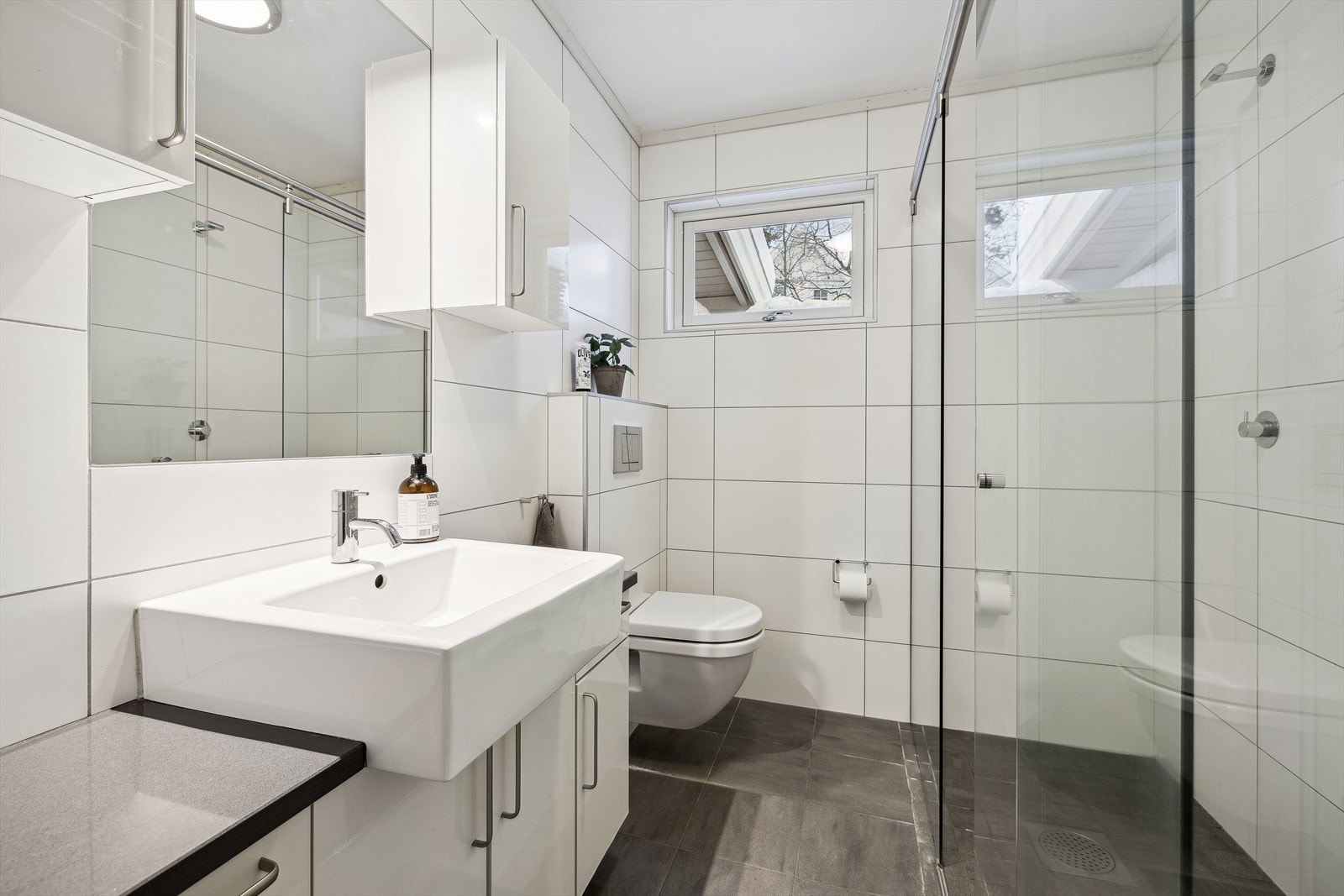 Flislagt bad med dobbel dusj og vegghengt toalett. Galleribilde