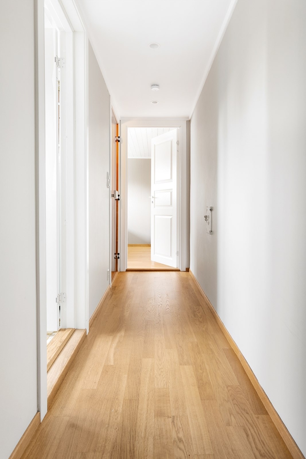 En gang med parkettgulv fører videre til soverommene og badet i første etasje. Galleribilde