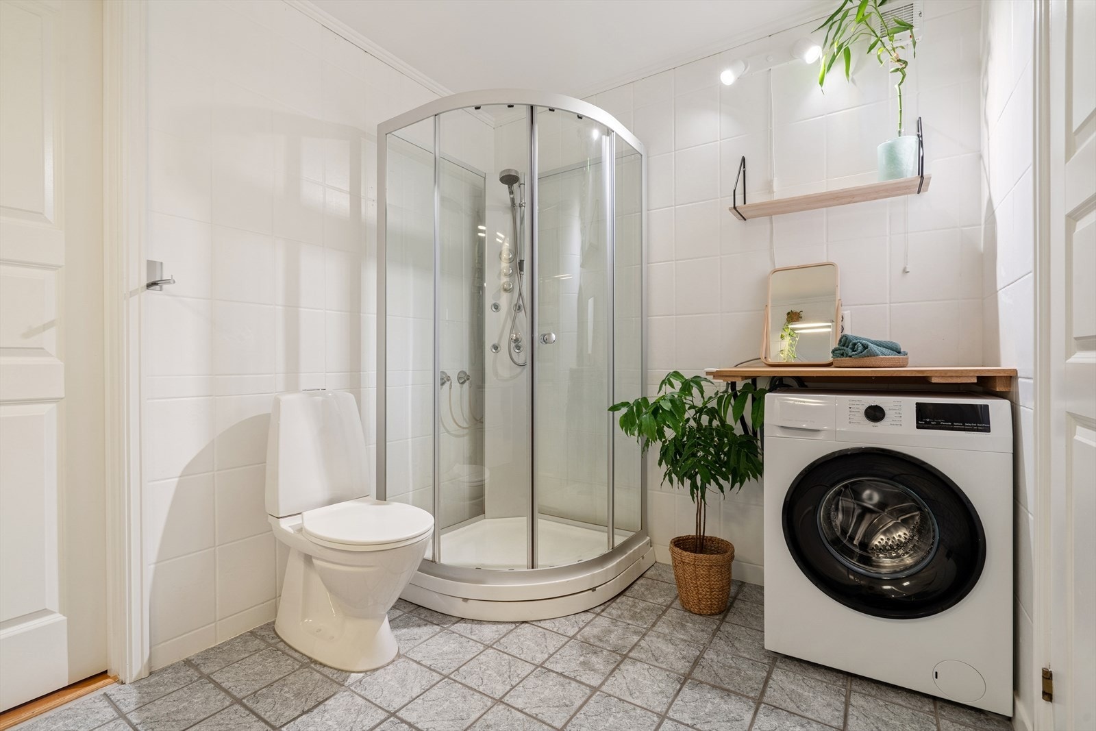 Lyst og funksjonelt baderom med plass til både vaskemaskin og tørketrommel. Galleribilde