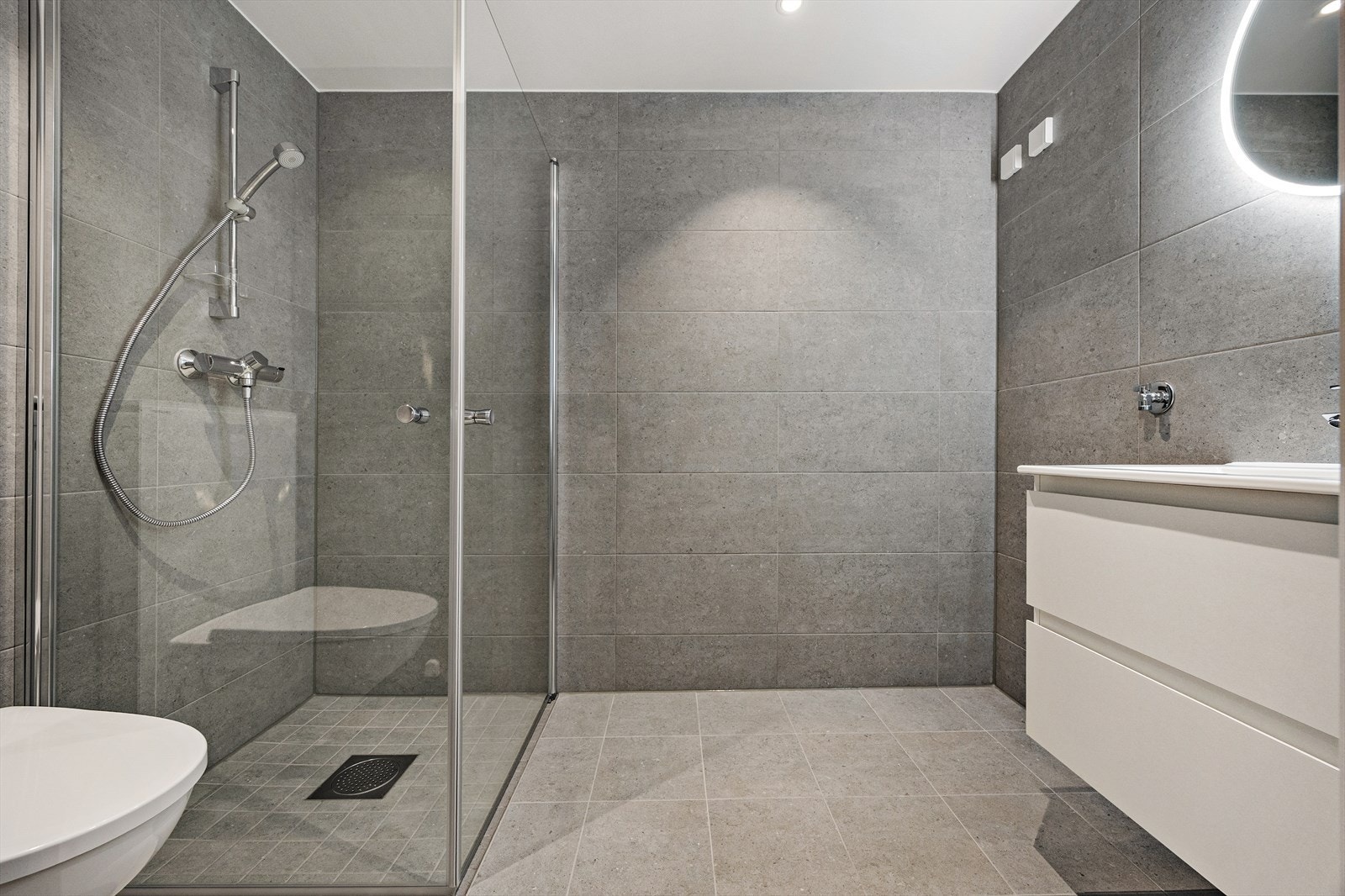 Badet er utstyrt med vegghengt toalett og et romslig dusjhjørne med glassdører. Galleribilde