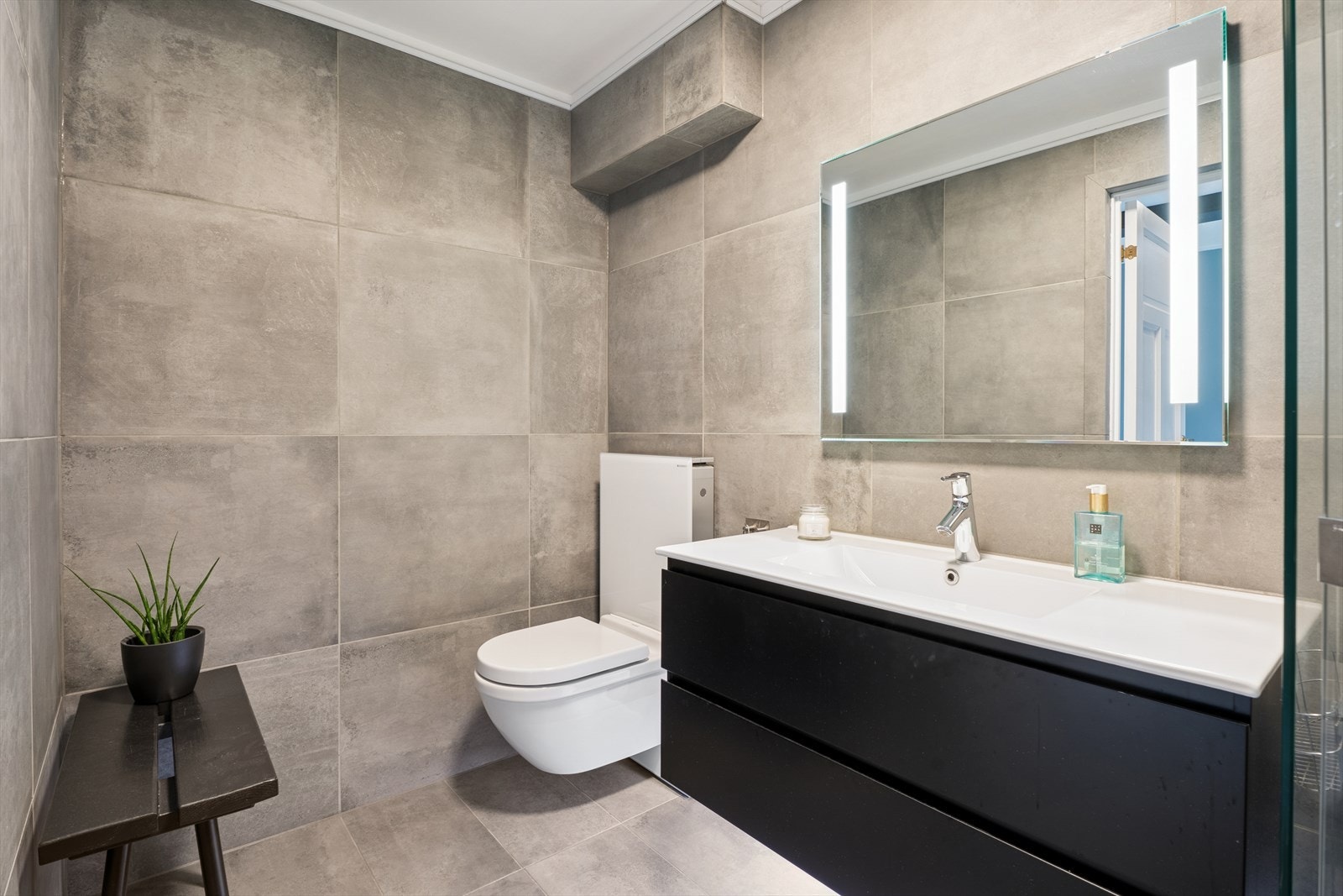 Badet har delikate gråbeige fliser på både gulv og vegger, kombinert med malte flater i himlingen Galleribilde