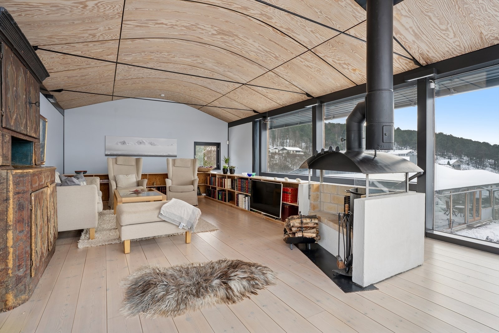 Den stemningsfulle peisen og de plassbygde bokhyllene under vinduene tilfører rommet både karakter og funksjonalitet Galleribilde