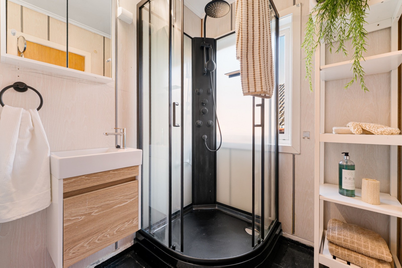 Boligens bad er praktisk innredet med dusjkabinett, håndvask med underskap og speilskap Galleribilde