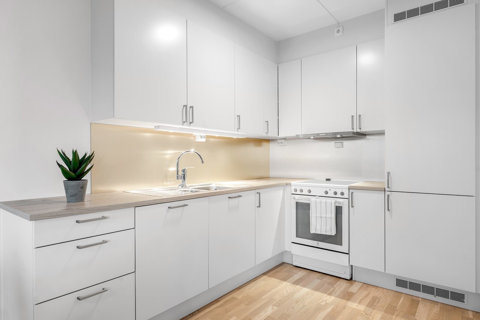 Flott kjøkken i hvit utførelse med glatte fronter, samt godt med oppbevaringsplass. Galleribilde