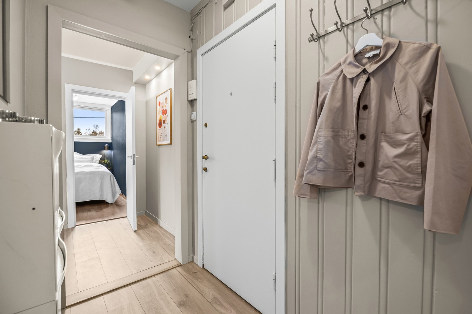 Entreen har 1-stavs laminatgulv, og både tak og vegger ble malt i duse farger i 2025.. Det er praktisk oppbevaring i skyvedørsgarderobe med speilfronter langs den ene veggen Galleribilde