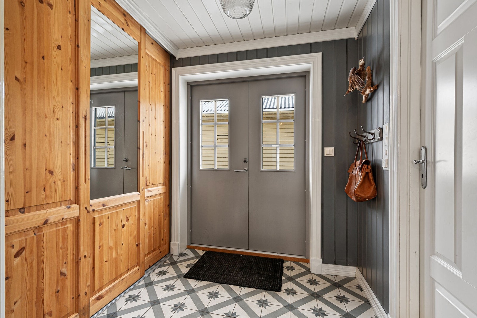 En romslig gang med skyvedørsgarderobe og dobbel ytterdør Galleribilde