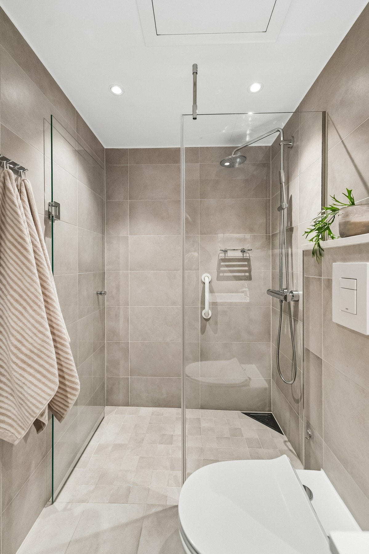 Flislagt bad med gulvvarme, vegghengt toalett og dusjsone med glassvegger. Galleribilde