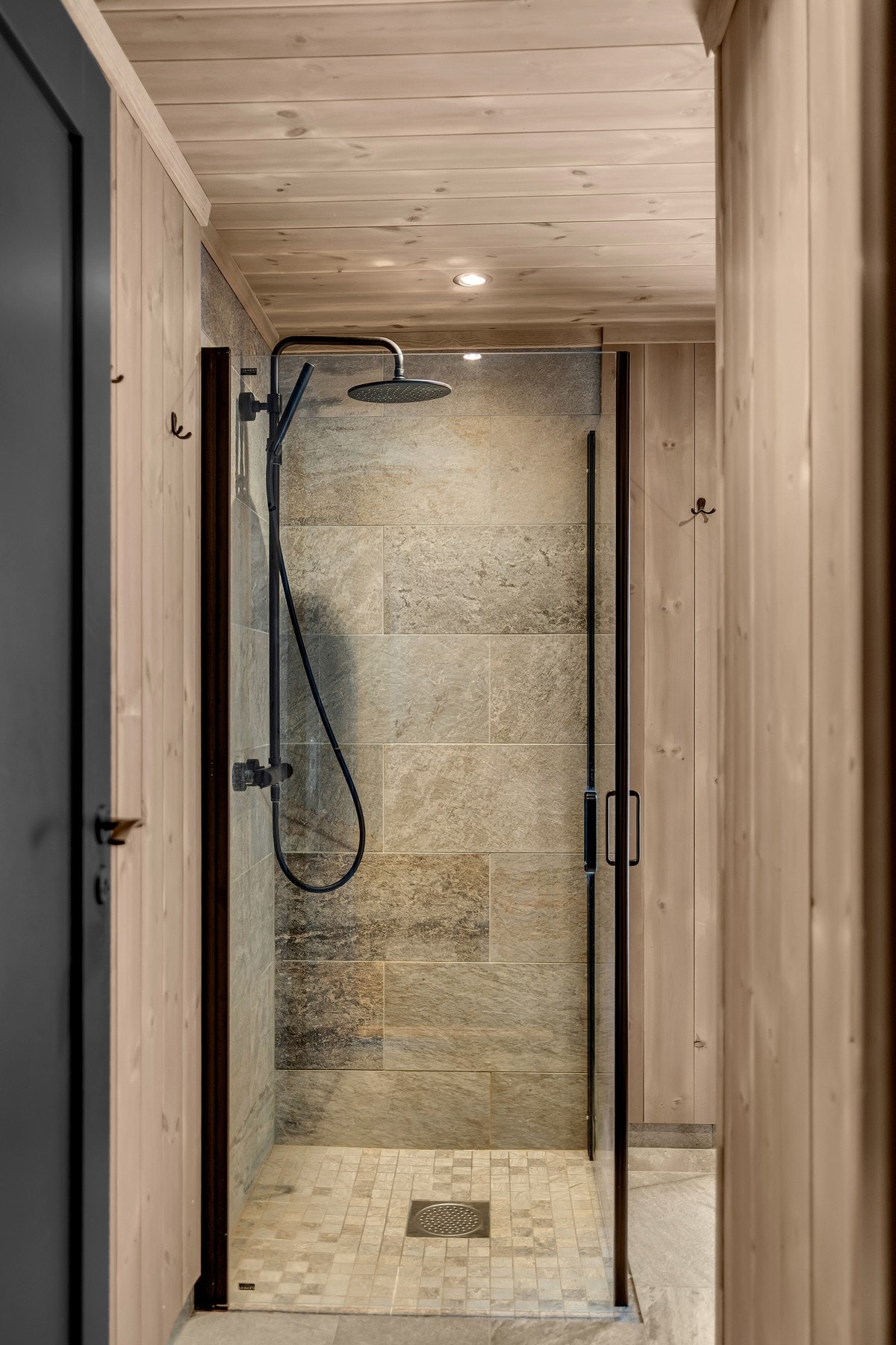 Veggene har behandlet trepanel som gir en lun og harmonisk hyttefølelse, mens dusjsonen er utført med keramiske fliser. Galleribilde