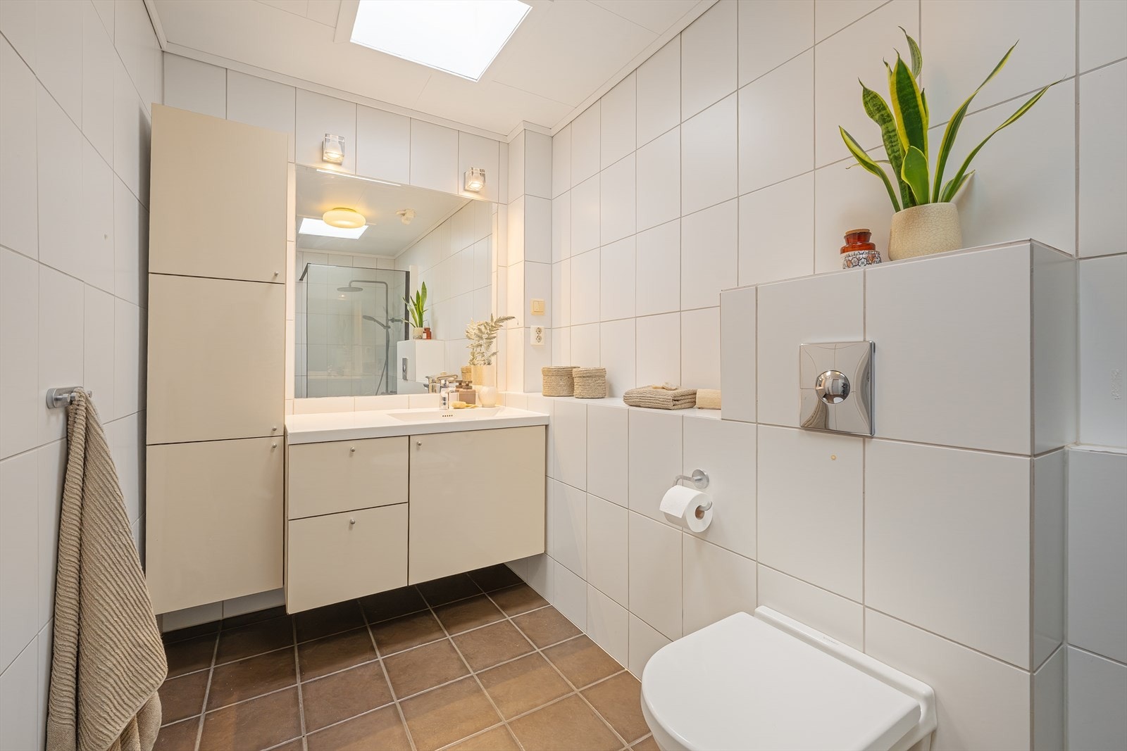 Pent og fliselagt baderom med vegg hengt toalett og dusj Galleribilde