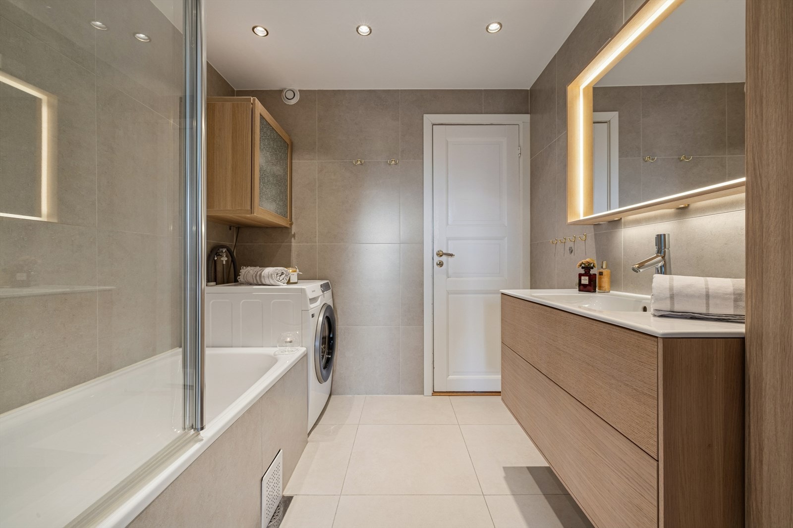 Badet fremstår som moderne og funksjonelt med oppgraderte overflater og innredning fra 2020. Rommet er helfliset i lyse overflater og har elektriske varmekabler i gulvet. Galleribilde