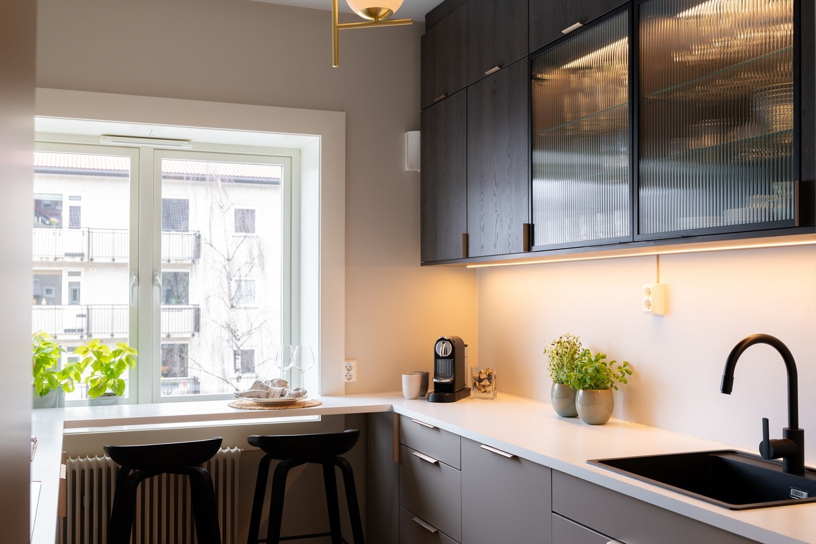 Kjøkkenet har slette, malte veggflater og fiskebeinsparkett på gulv, som gir et helhetlig og moderne uttrykk Galleribilde