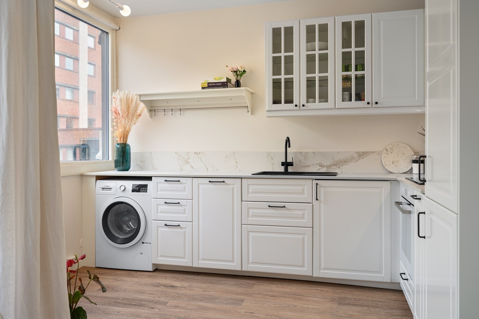 Innredning med opplegg for vaskemaskin og mekanisk avtrekksvifte over stekesonen. Galleribilde