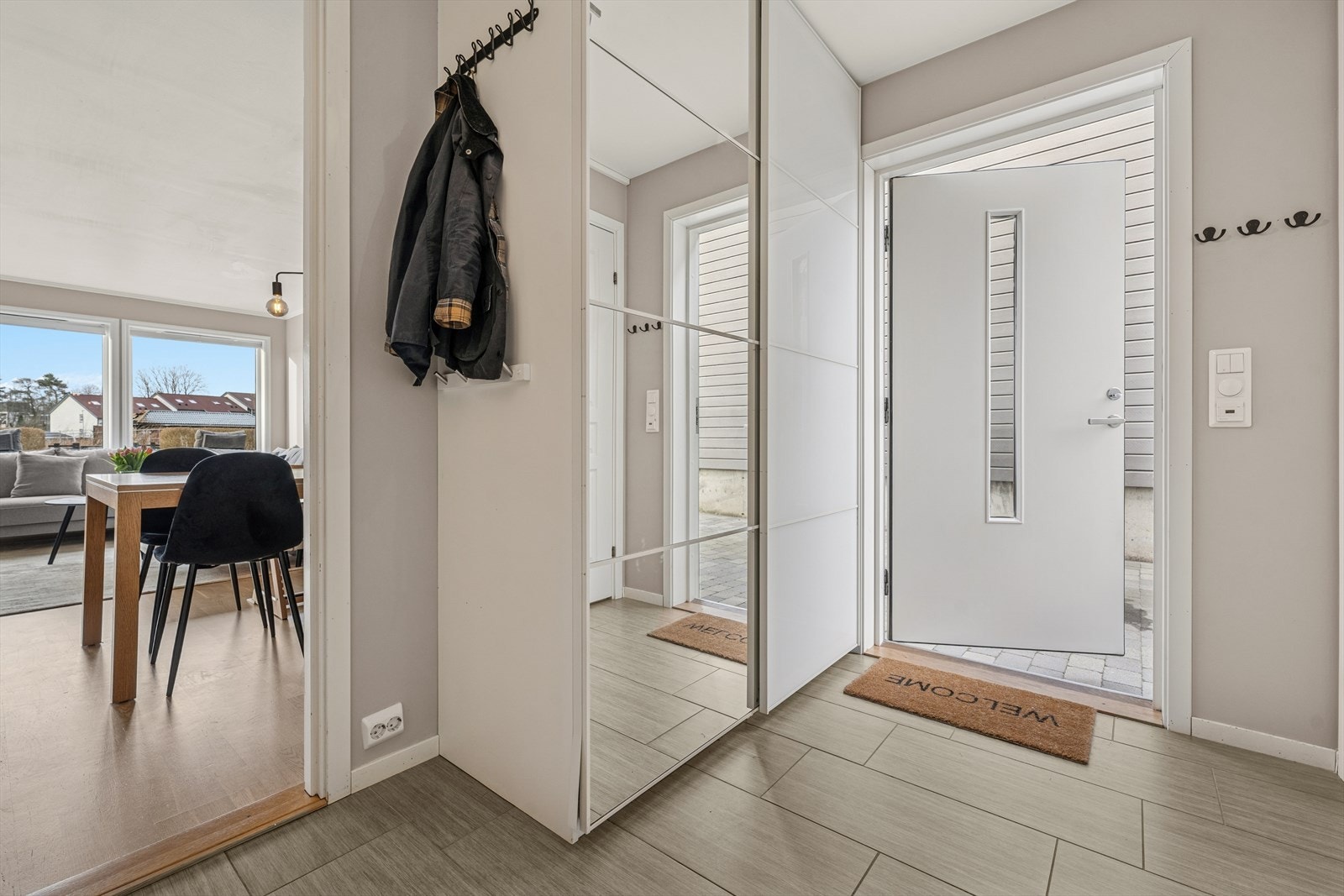 Man ønskes velkommen inn i en romslig entré som er praktisk innredet med flislagt gulv og stor garderobe som gir god lagringsplass til yttertøy og sko. Galleribilde
