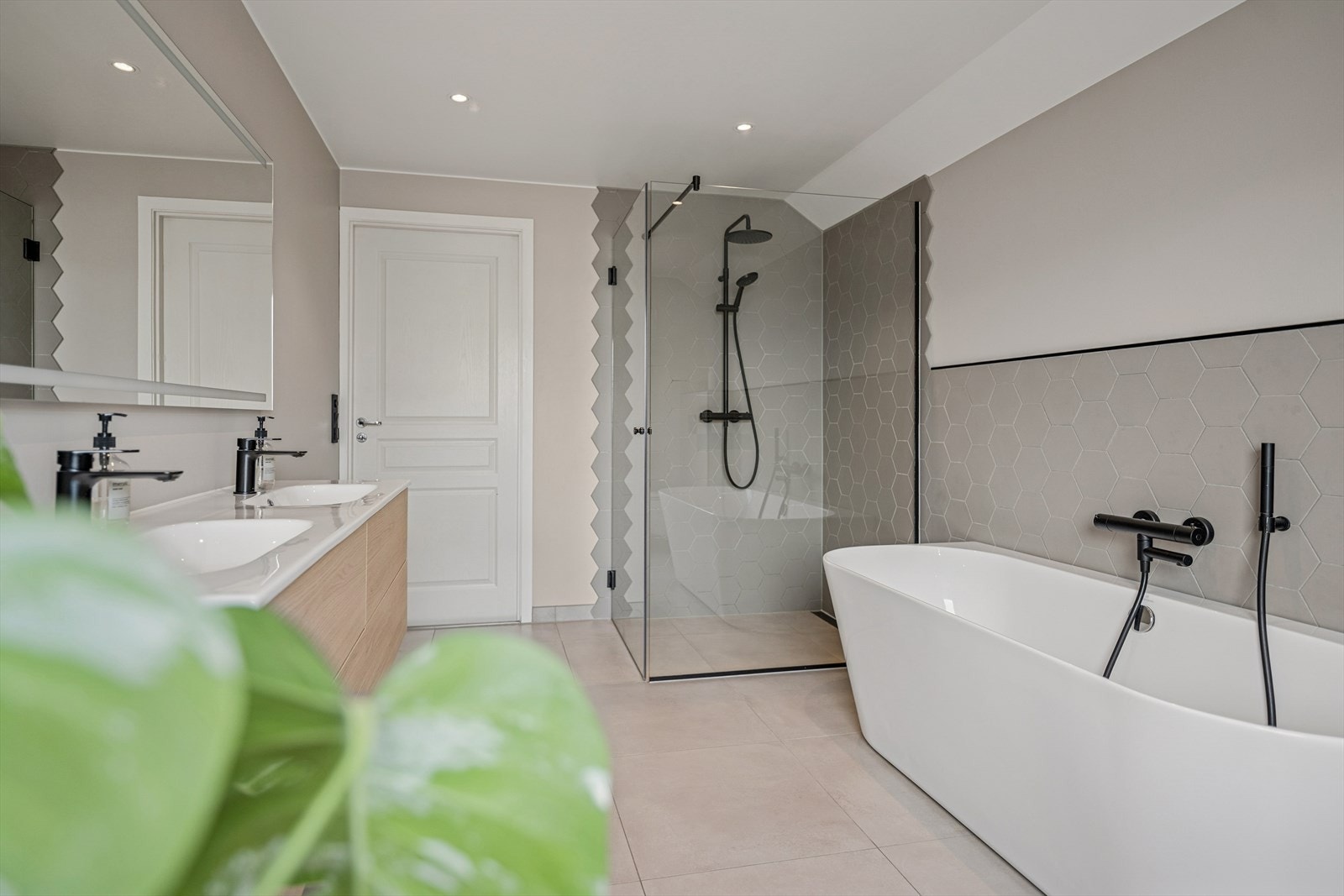 Badet er ellers utstyrt med dusjhjørne, badekar, vegghengt toalett og baderomsinnredning med god lagringsplass og dobbel, nedfelt servant. Sorte detaljer er gjennomgående og gir et stramt og moderne uttrykk. Galleribilde