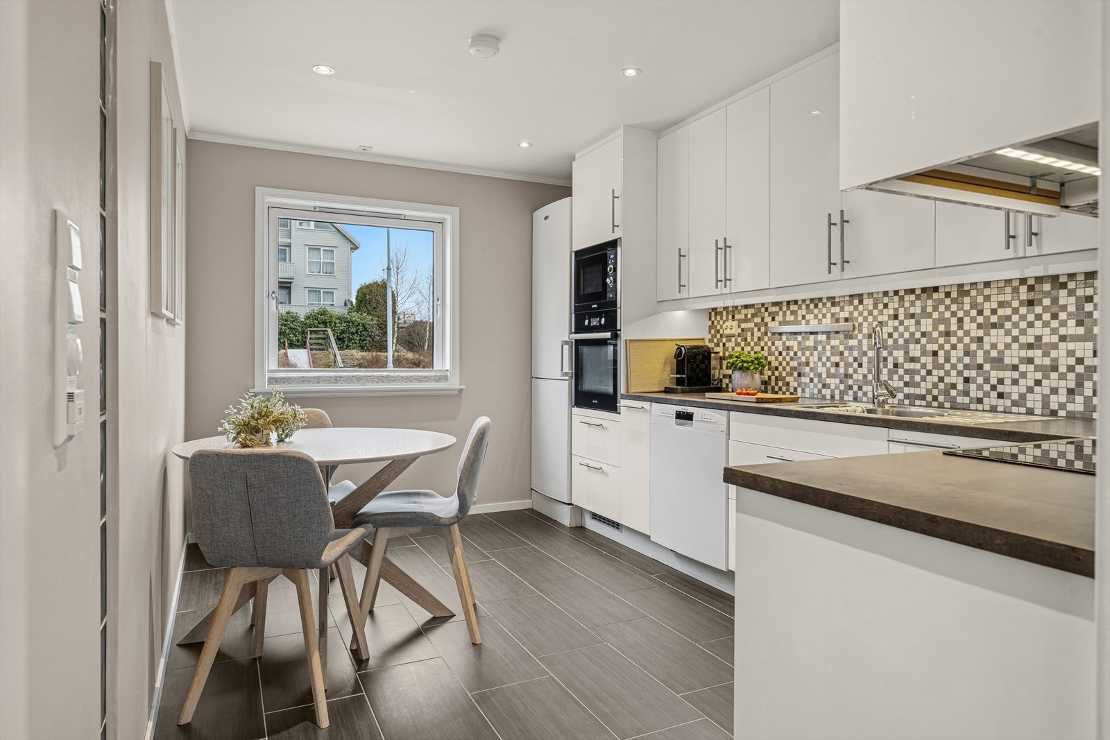 Kjøkkenet ble byttet i 2015 og er stilrent innredet med hvite, slette fronter og grå benkeplate i laminat. Et stort og godt kjøkken hvor man har rikelig med skap- og skuffeplass, samt gode arbeidsflater på benk. Galleribilde