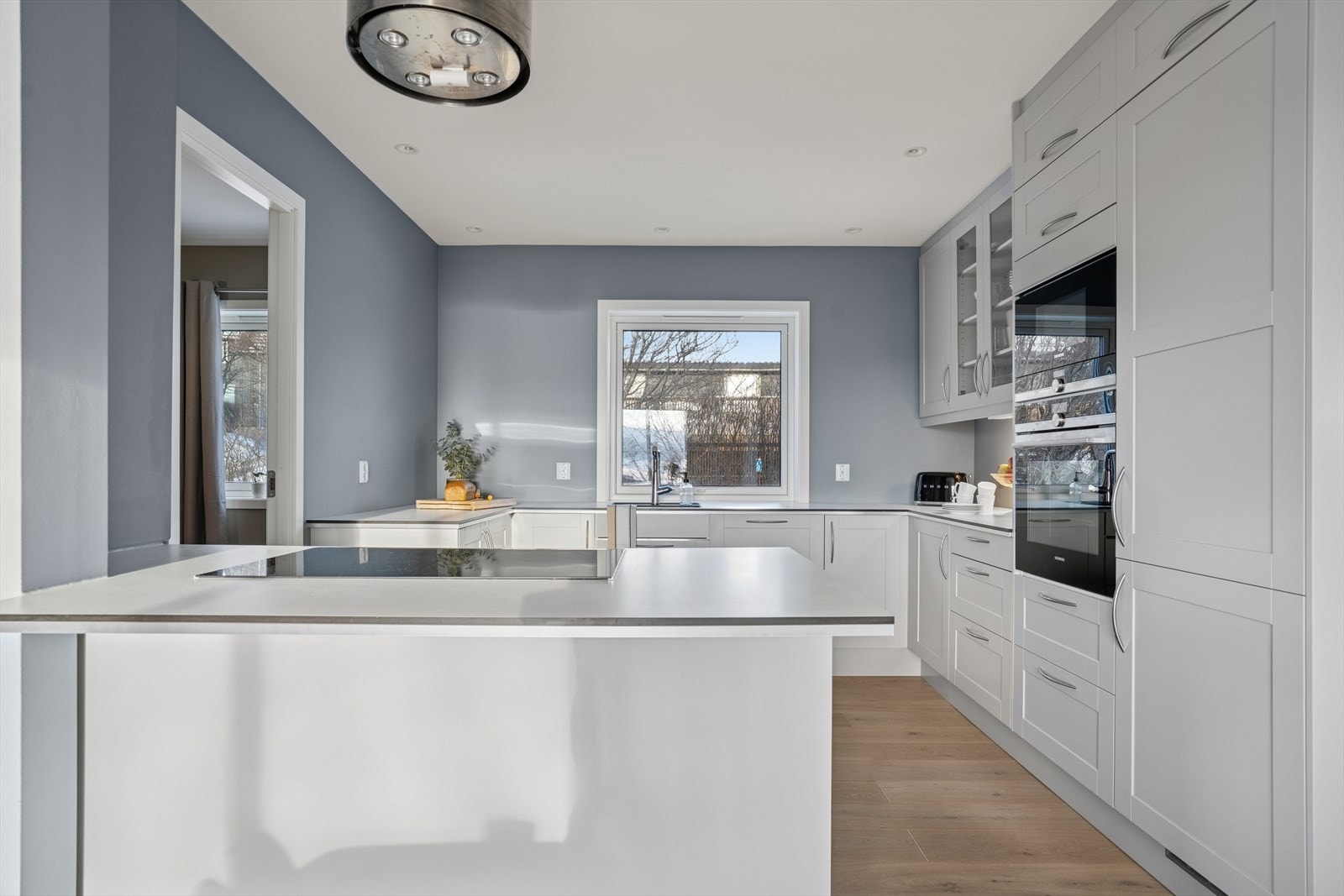 Kjøkkenet har en moderne innredning fra 2023 med kjøkkenøy mot stuen som skaper et naturlig romskille Galleribilde