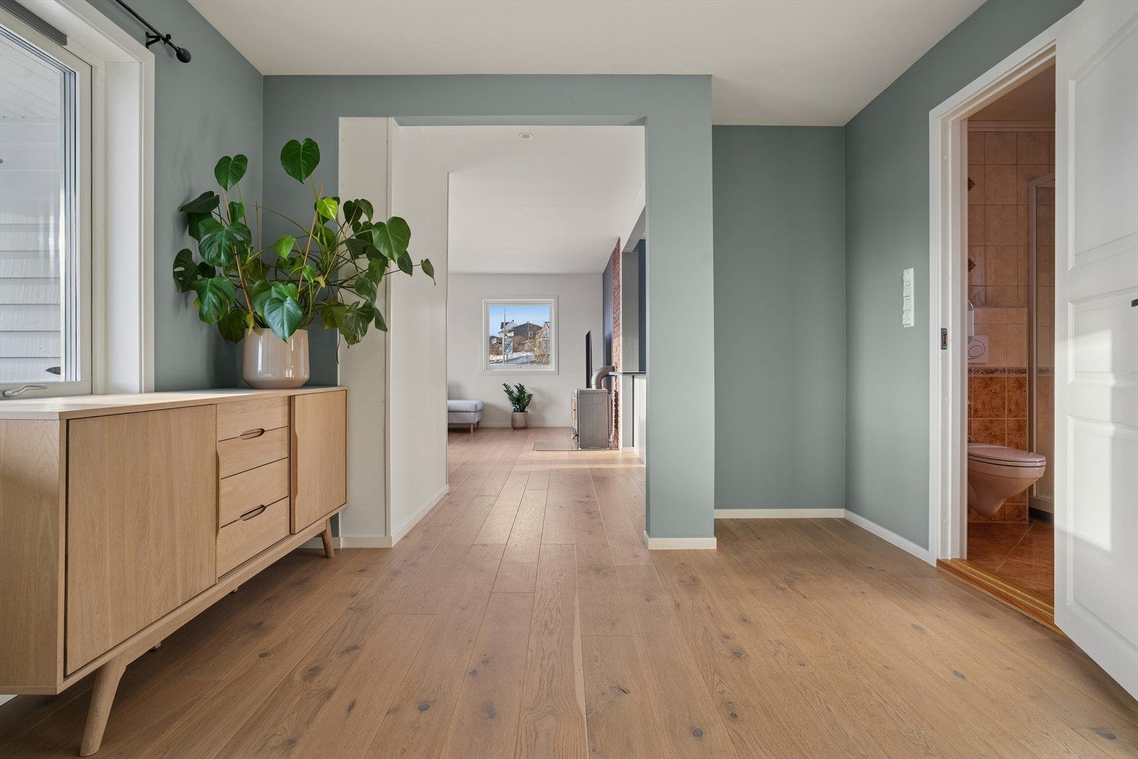 Fra entréen kommer du videre inn i gangen som kobler hele etasjen sammen - Herfra får du enkel tilgang til både bad, stue og soverom, noe som gir en praktisk og godt gjennomtenkt planløsning Galleribilde