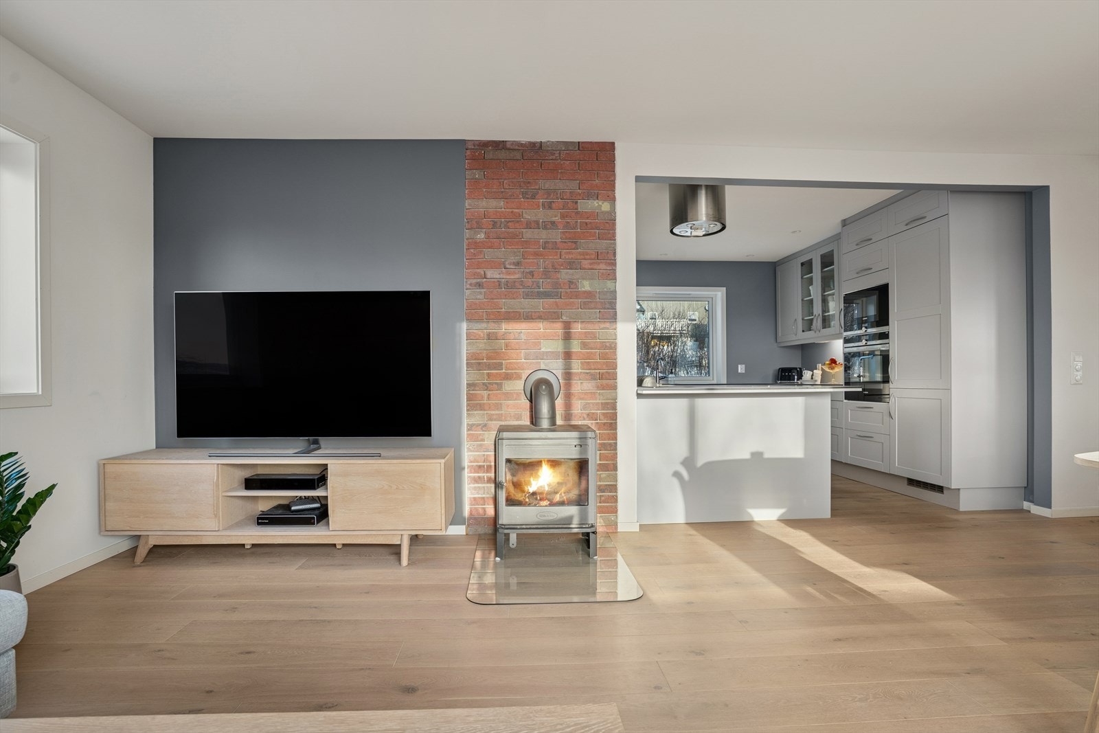 Den åpne løsningen mellom stue og kjøkken skaper en luftig og innbydende atmosfære Galleribilde