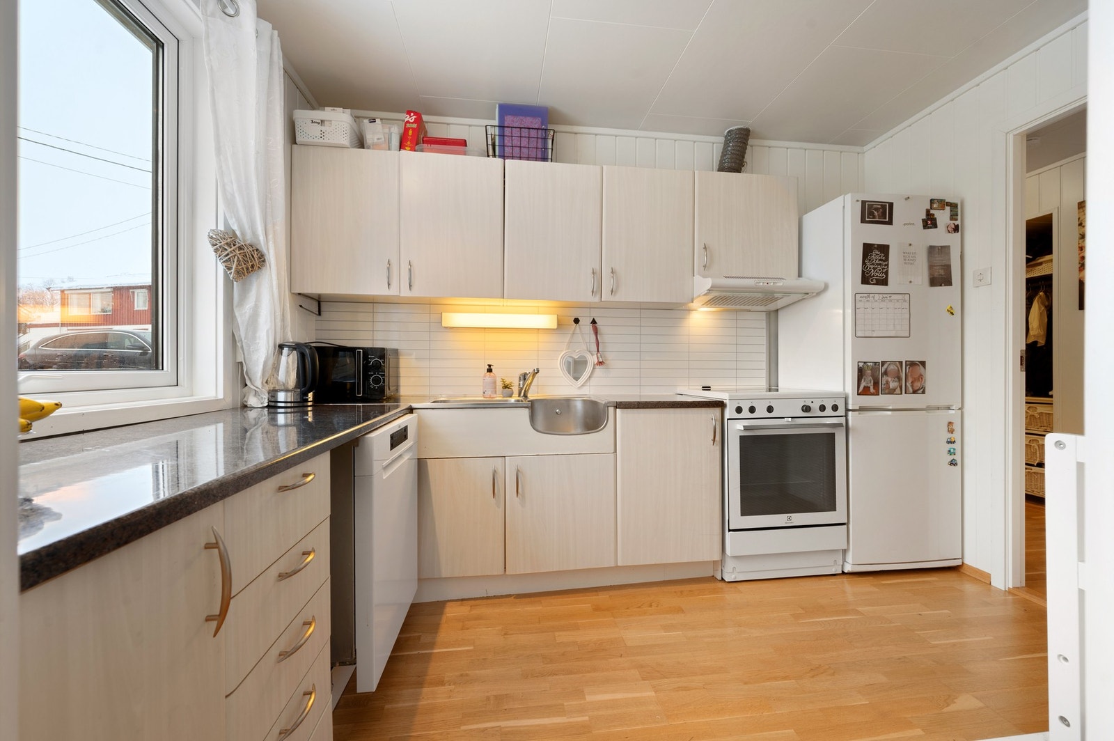 Kjøkkenet har slette hvitmalte fronter, samt godt med skap- og benkeplass Galleribilde