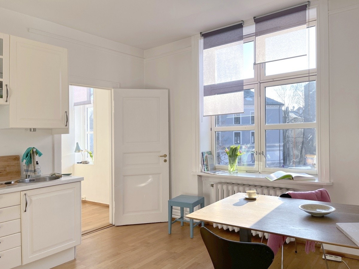 Lyset i leiligheten, spisebord og dør inn til et lite soverom. Galleribilde