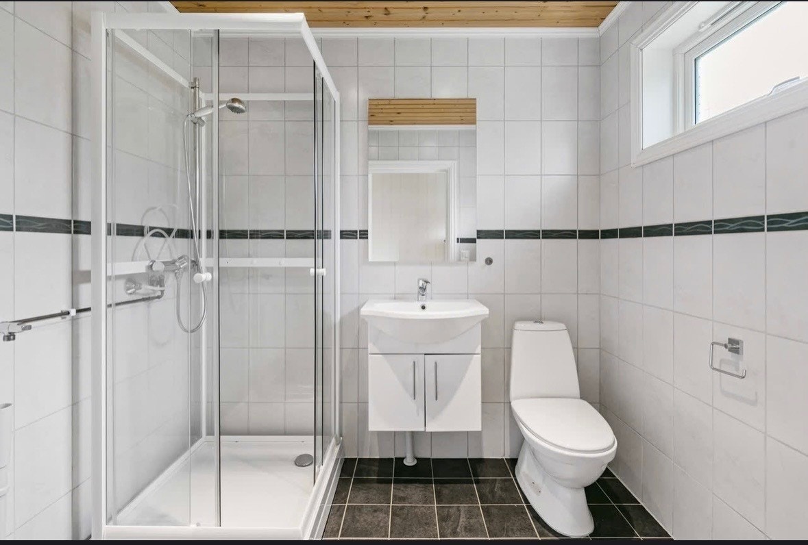 Badet i leiligheten er flislagt og har dusjkabinett og varmekabler i gulvet. Galleribilde