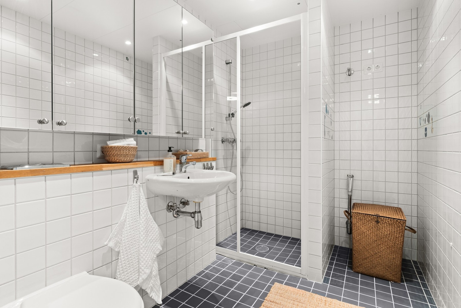 Romslig, flislagt baderom med varmekabler i gulv og downlights i himling Galleribilde