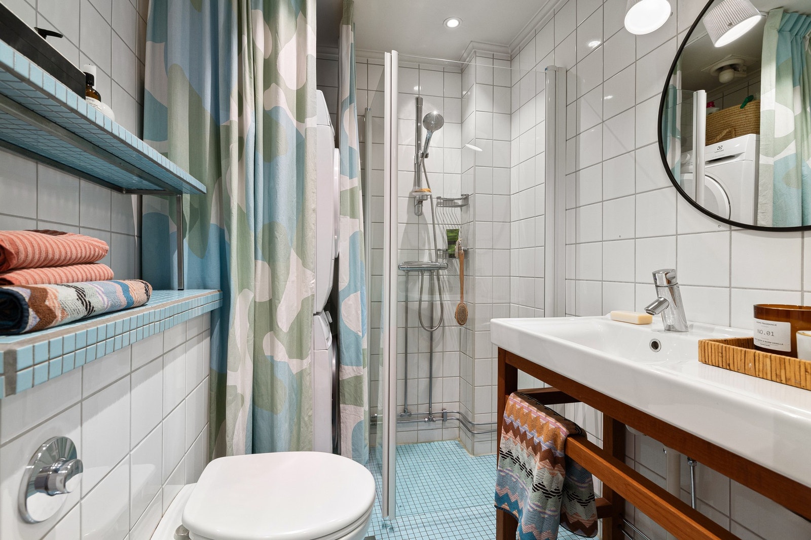 Badet er fra 2004 og er innredet med dusjhjørne med glassdører, vegghengt toalett og servant med speil over. Det er opplegg for vaskemaskin, noe som gir en praktisk og plassbesparende løsning. Gulvet er belagt med mosaikkfliser og har elektriske varmekabl Galleribilde