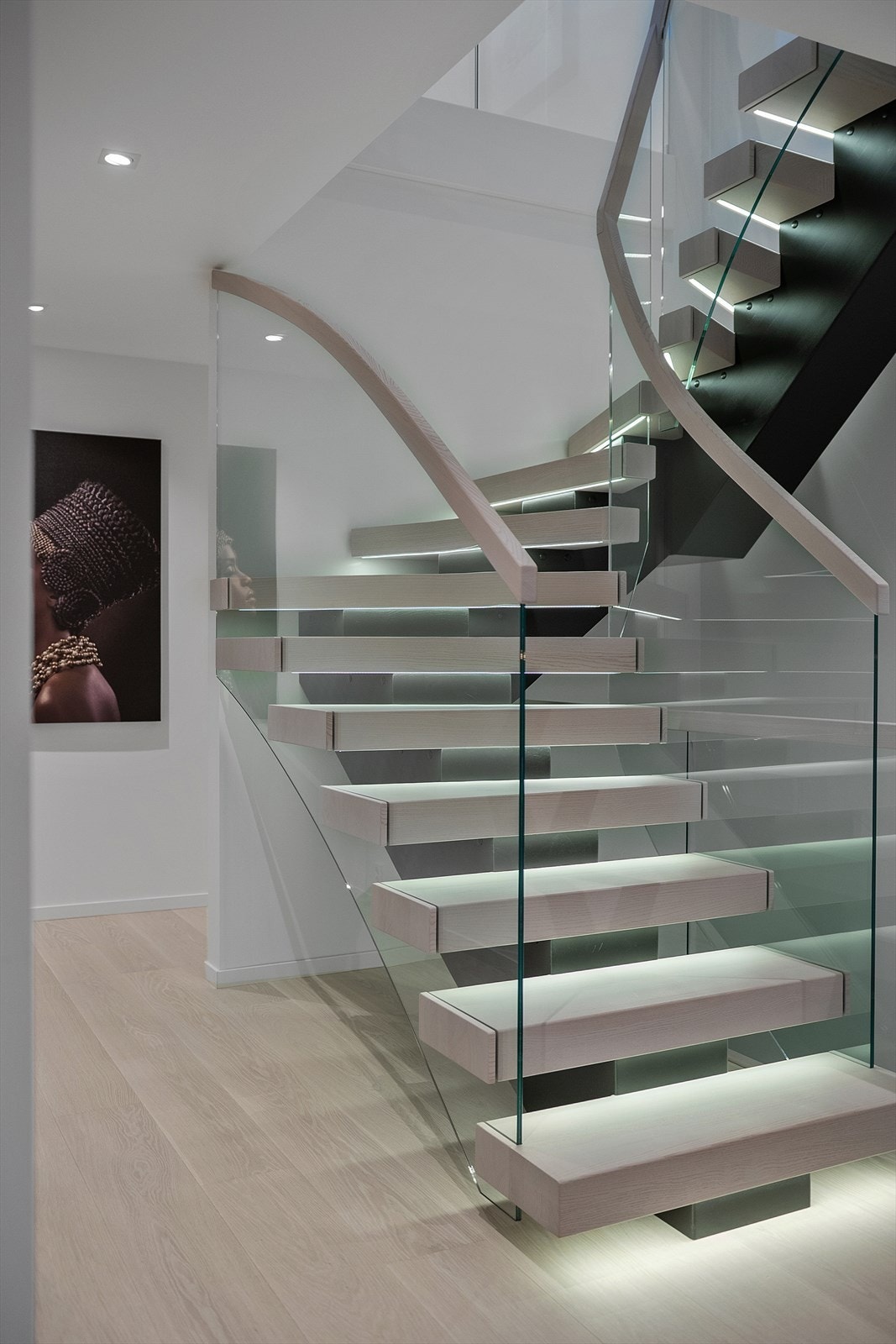 Vi beveger oss ned til boligens 1.etg via en eksklusiv trappeløsning med flytende trinn, glassrekkverk og integrert belysning som gir et unikt preg. Galleribilde