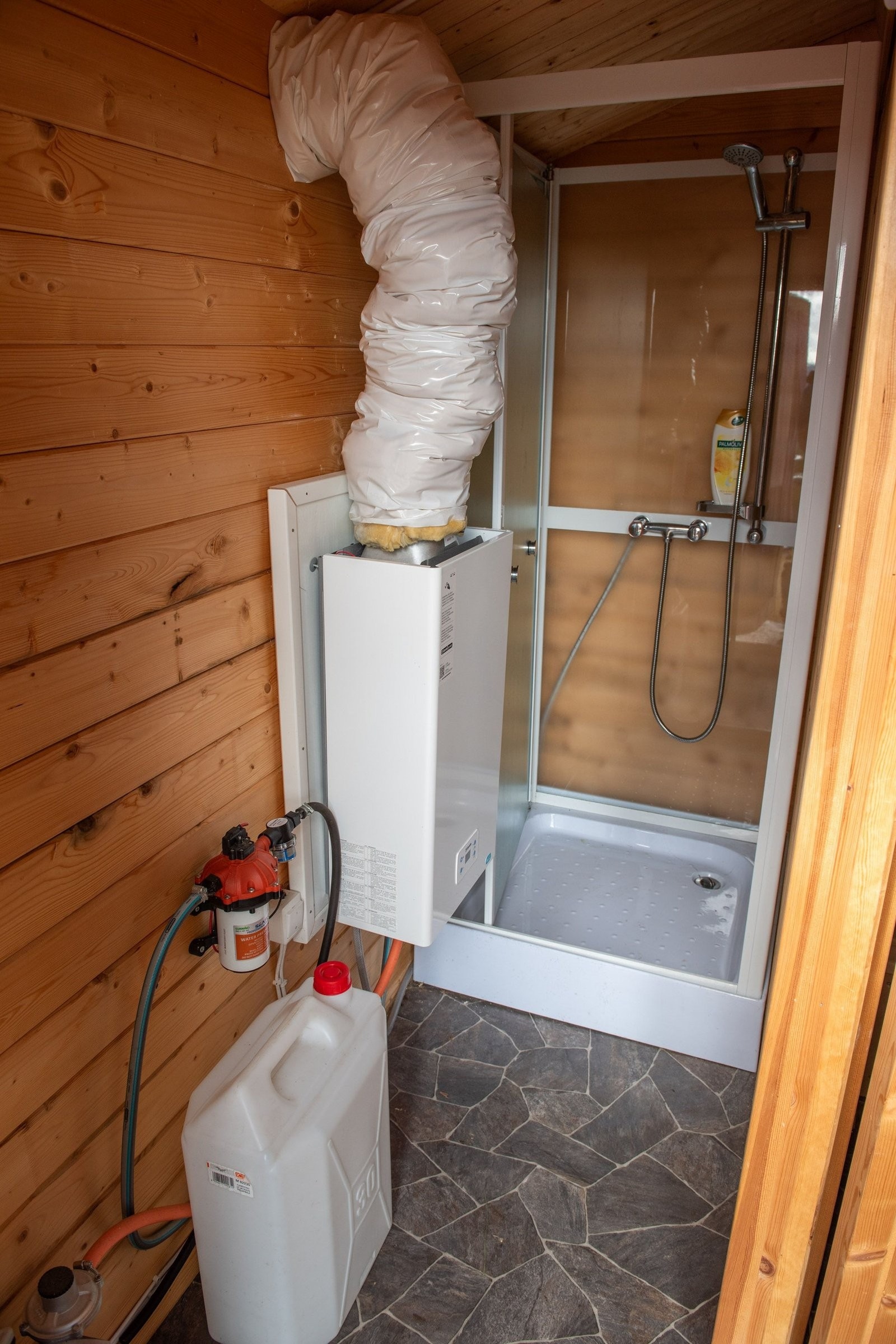 Gassvarming av vann til dusj, er montert trykkpumpe for vannet på veggen. Strøm til pumpe, lys og avtrekk med strøm fra solcelle via batteri i hovedhytte. Galleribilde