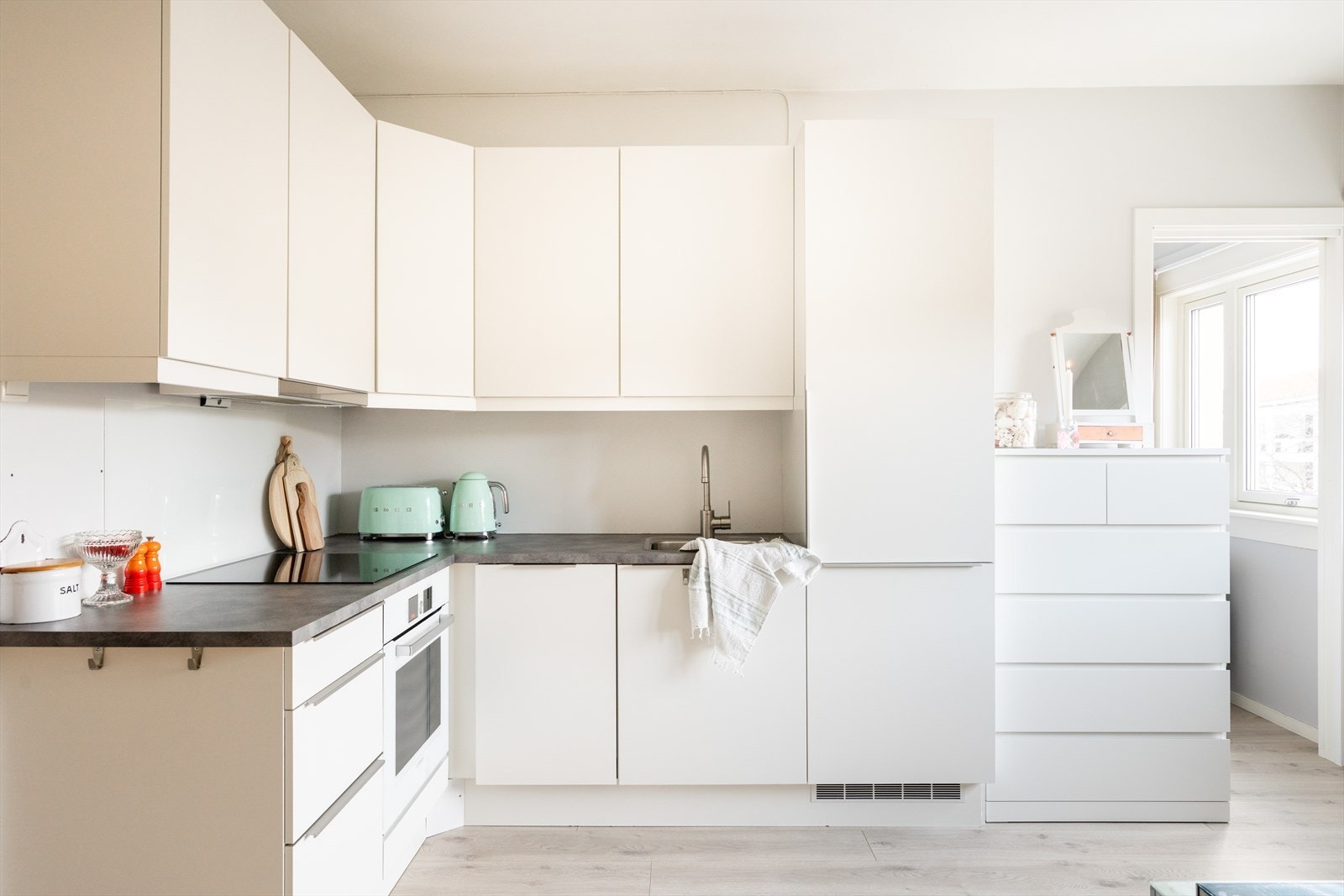 Kjøkkenet er et stilrent HTH-kjøkken fra 2016 med glatte fronter og laminert benkeplate med nedfelt utslagsvask. Galleribilde