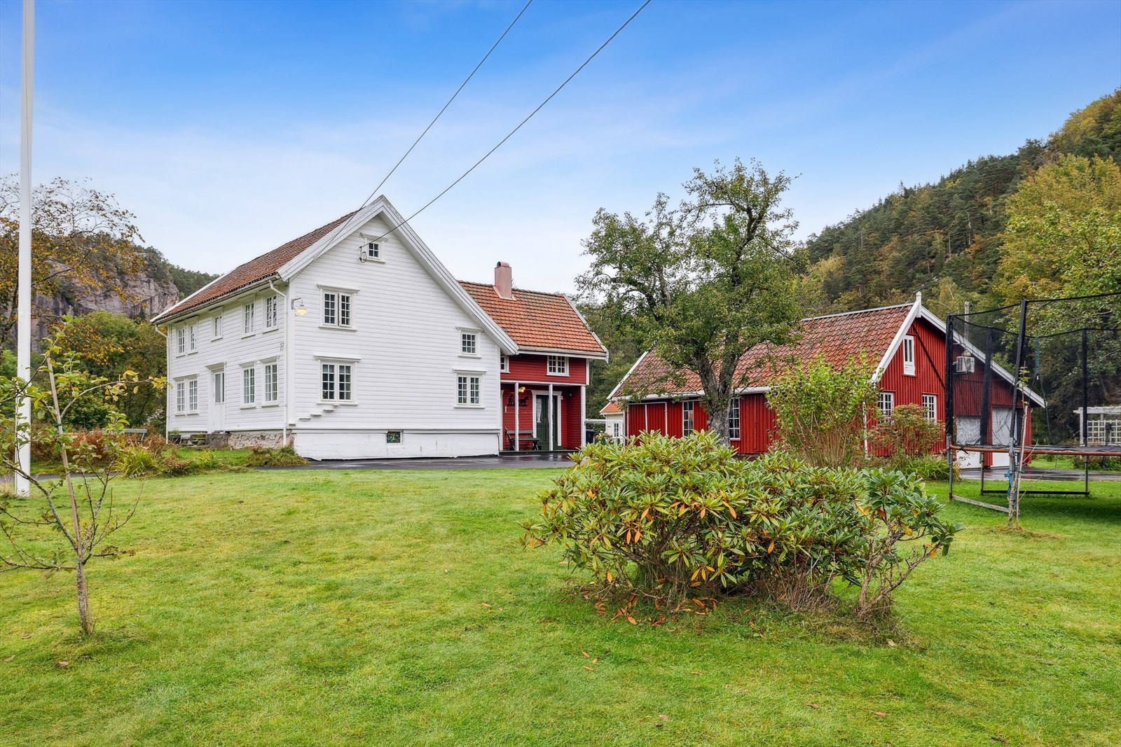 Stor hage med plen, busker og trær. Det er også flaggstang på eiendommen Galleribilde