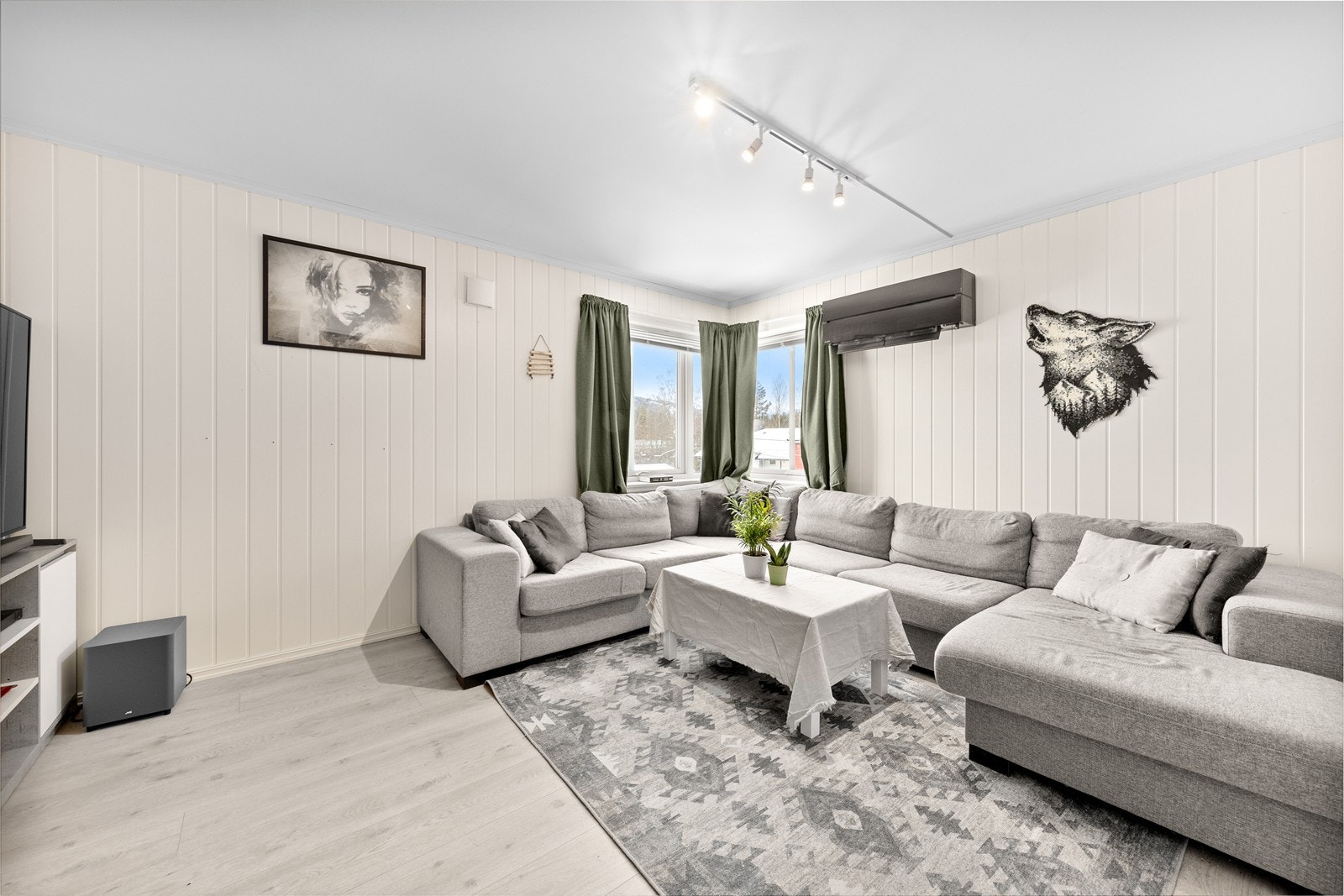 Pen stue med 1-stavs laminat på gulv og hvitmalt panel på vegger. Galleribilde