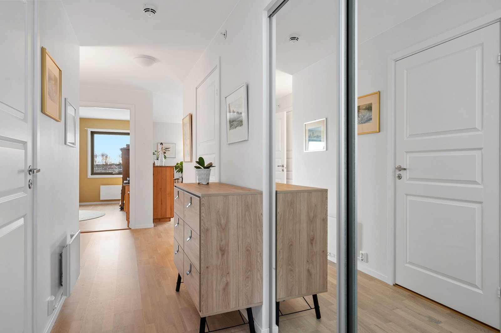 En lys og innbydende entré ønsker deg velkommen inn i denne moderne leiligheten. Galleribilde