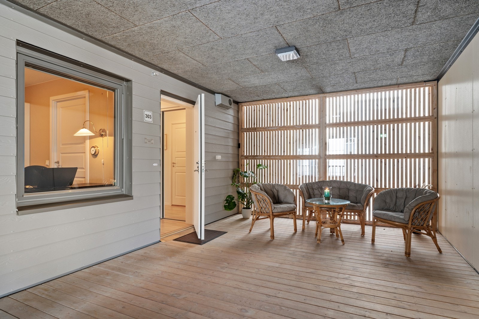 Overbygget svalgang med plass til en liten sittegruppe ved inngangspartiet. Galleribilde