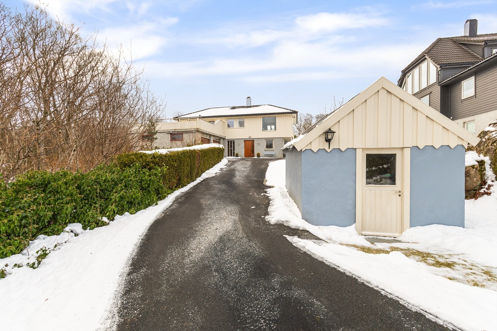 Fin fasade med hekk og grønne omgivelse som skaper et innbydende førsteinntrykk. Galleribilde