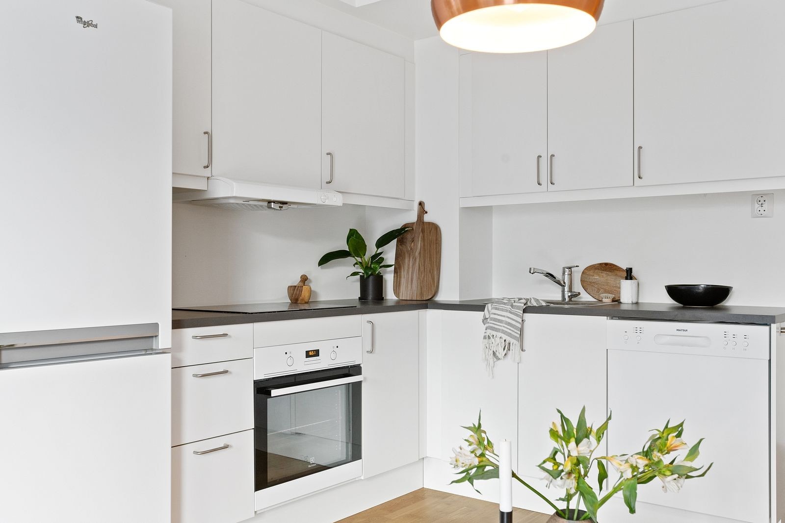 Pent kjøkken som har godt med skapplass, oppvaskmaskin, kjøleskap, og ovn. Galleribilde