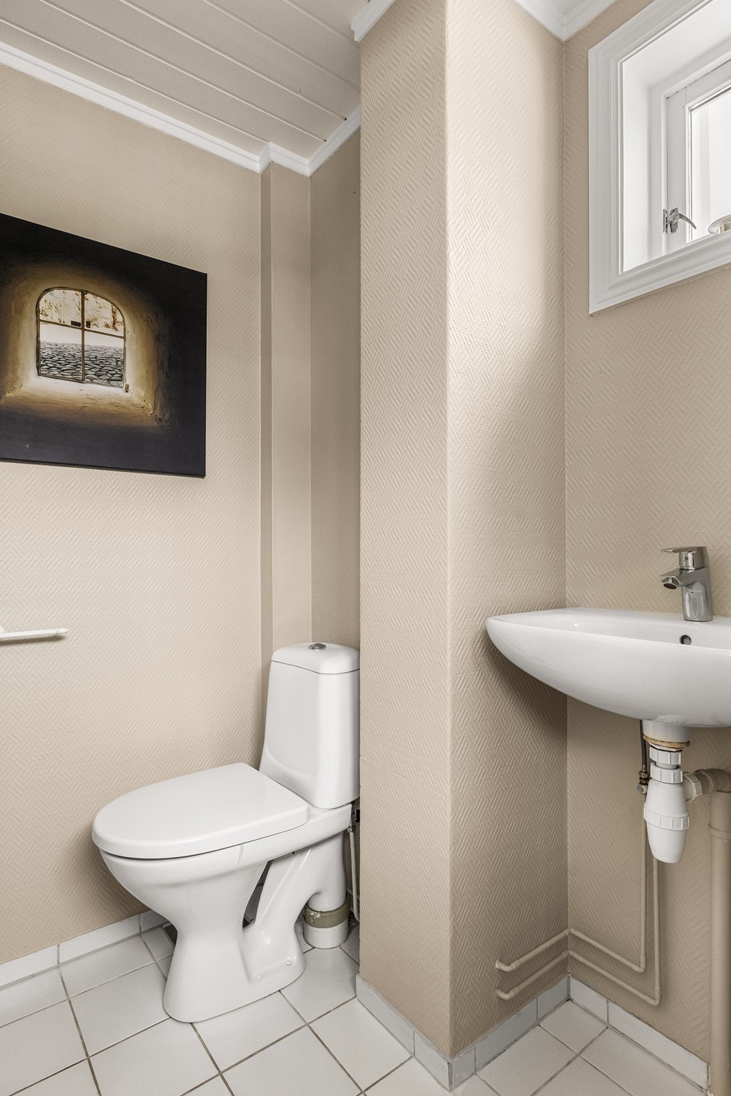 Praktisk WC-rom i første etasje med flislagt gulv, toalett og servant. Galleribilde