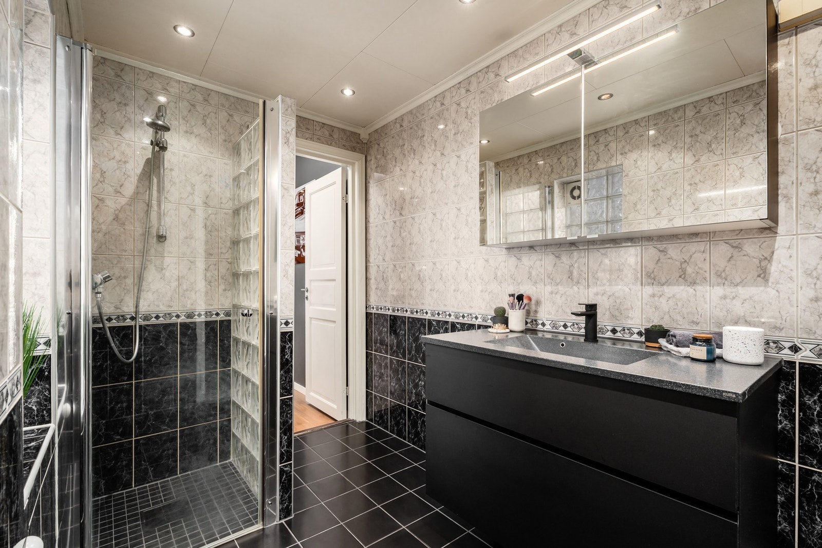 Flott, helfliset bad med gulvvarme. Servantinnredningen i sort har praktiske, romslige skuffer, helstøpt servantplate, speilskap og god belysning over. Galleribilde