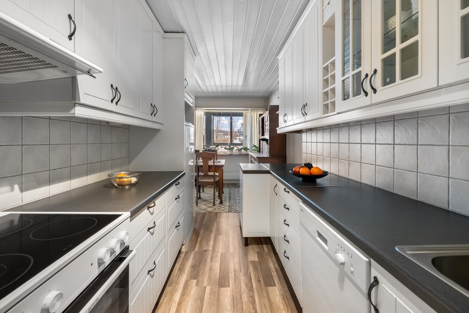 Hvite, profilerte fronter og laminert benkeplate skaper et ryddig kjøkken. Galleribilde