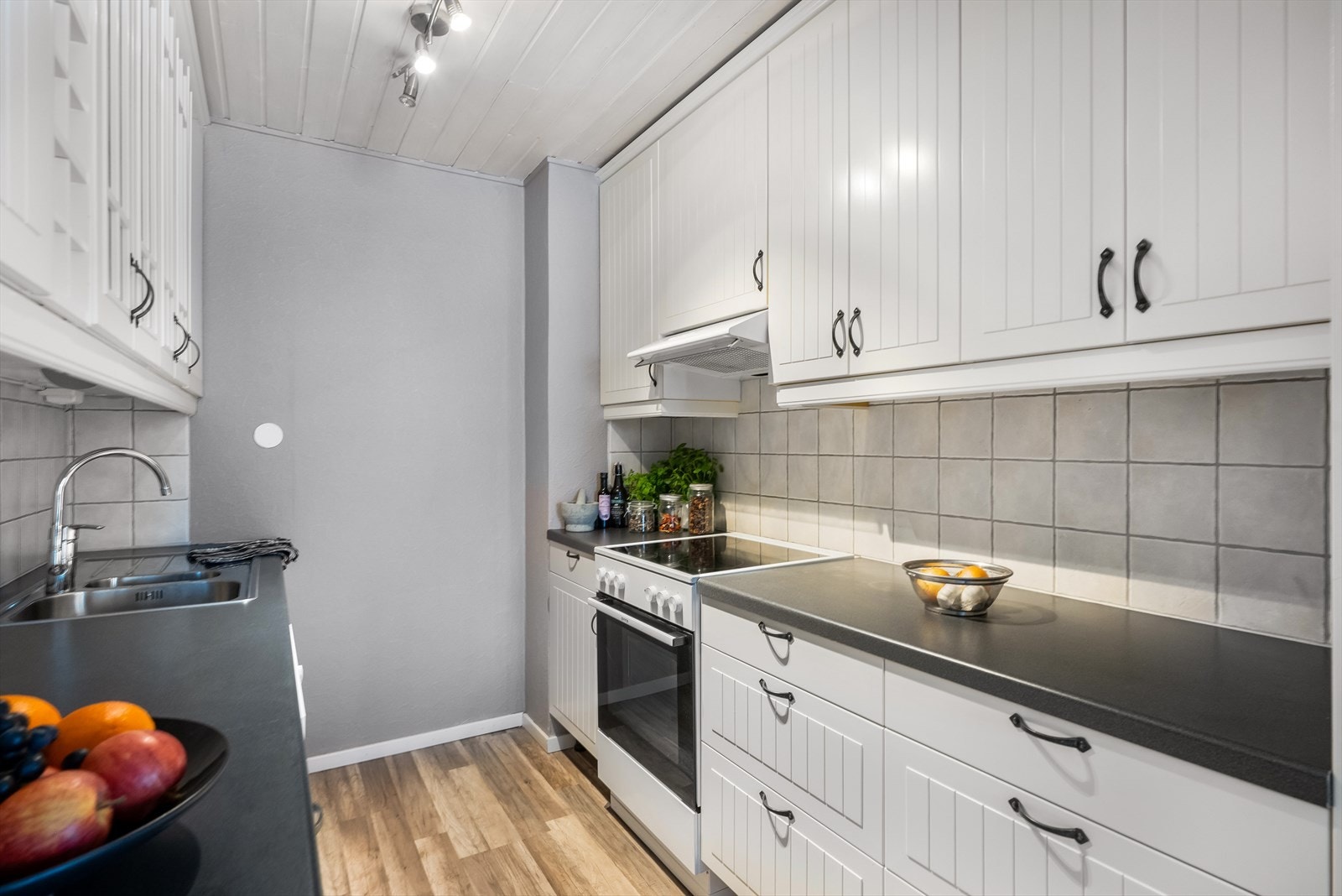 Kjøkkenet har fliser på vegg over benkeplaten og integrerte hvitevarer. Galleribilde