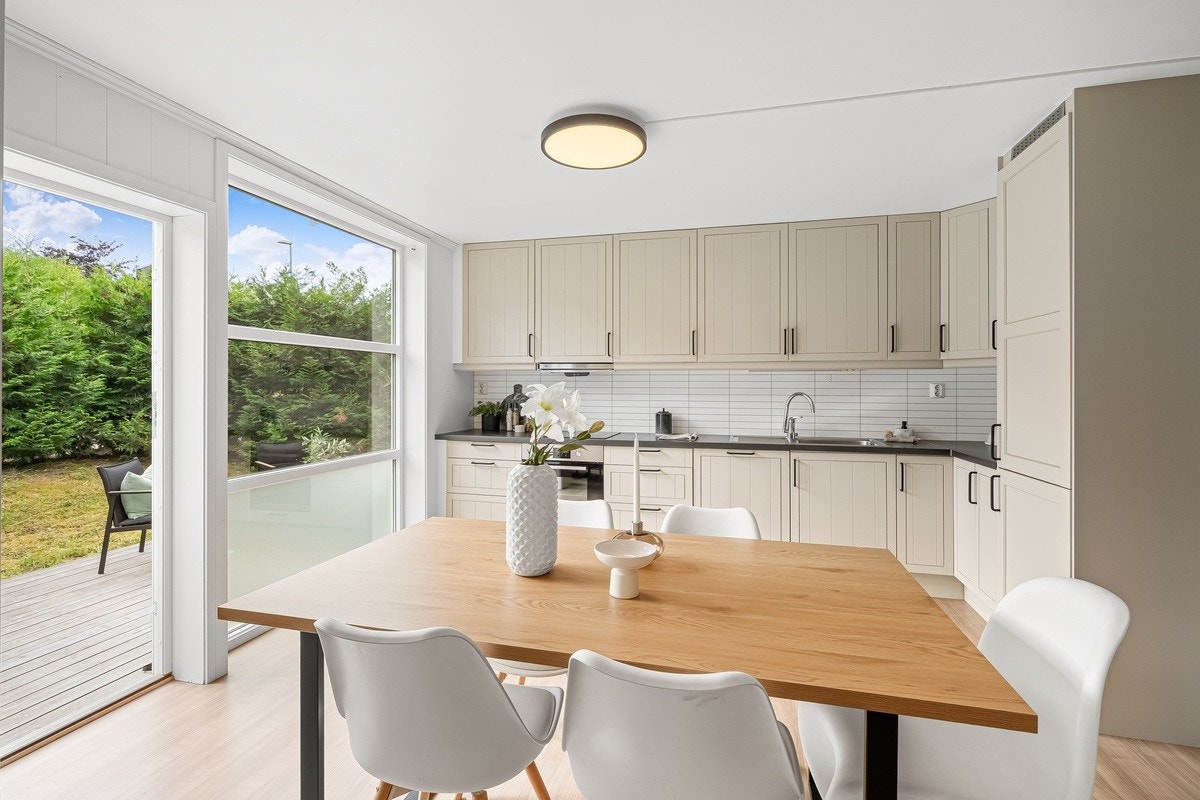 Stort kjøkken med egen spisesone. Kjøkken i en råstilig beige-farge, fullt utstyr med alt du trenger av integrerte hvitevarer og kjøkkenutstyr. Galleribilde