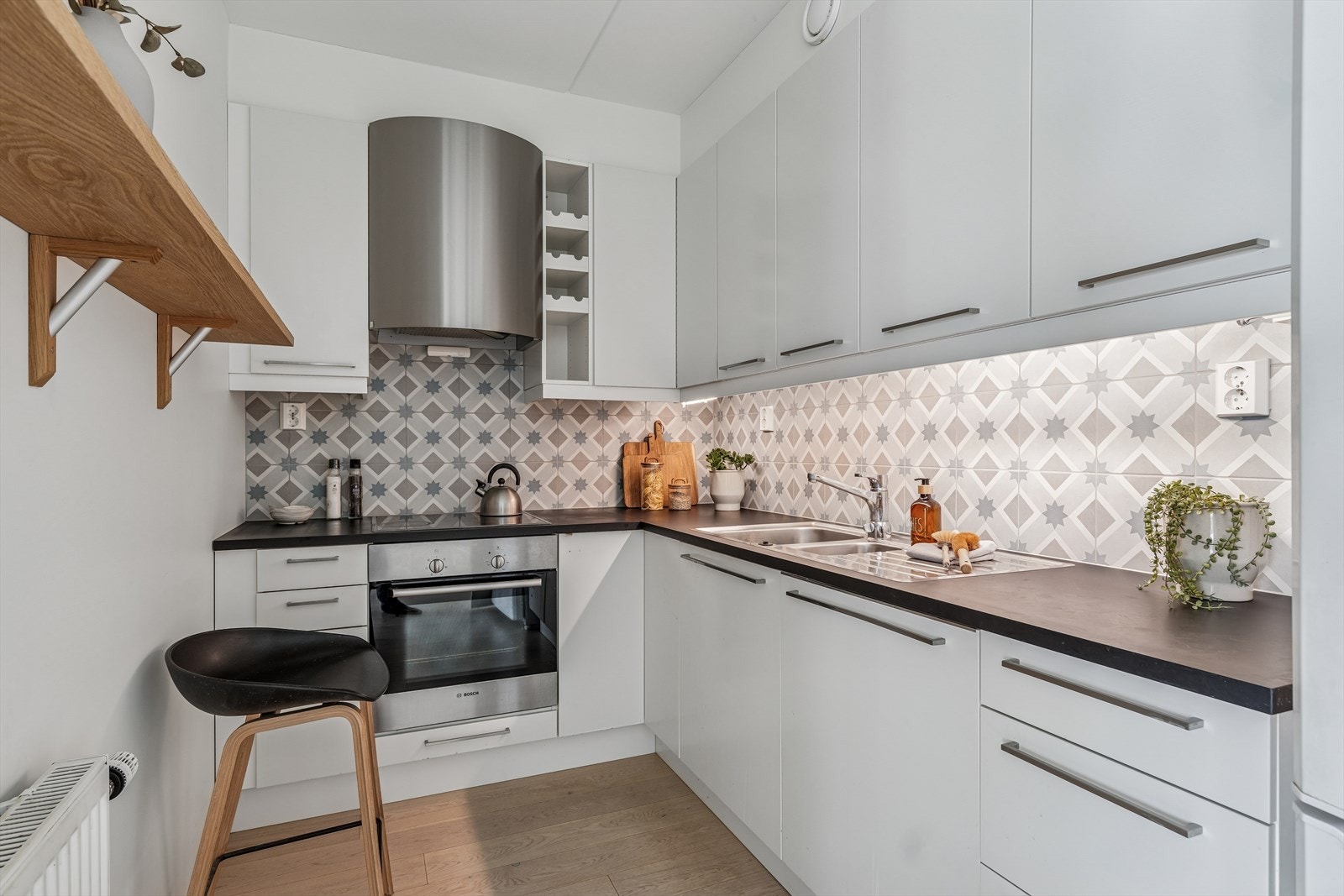 Pent og funksjonelt kjøkken i hvit farge fra 2012 med takhøye skap, glatte fronter og stål håndtak . Galleribilde