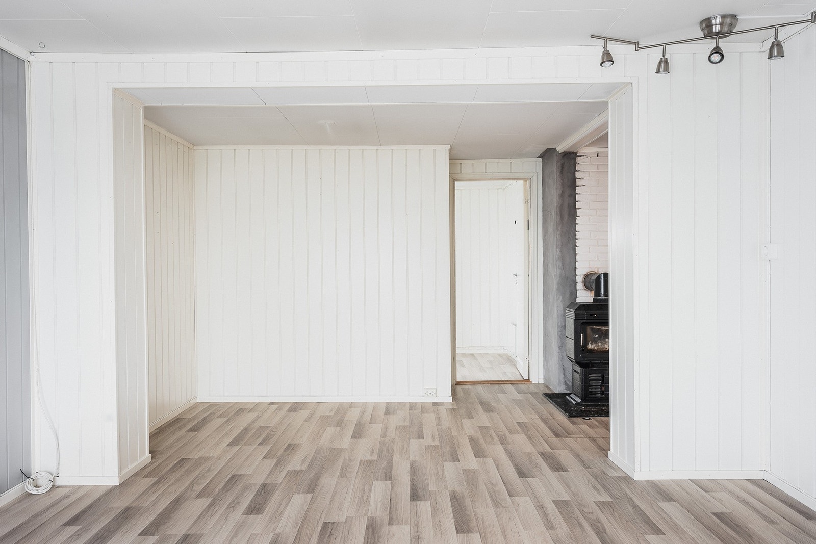 Peisovnen på kjøkkenet varmer også opp stuen, og veggene er kledd med panelplater malt i hvitt og lysegrått. Stuen innbyr til hygge fra tidlig morgen til sent på kveld. Galleribilde