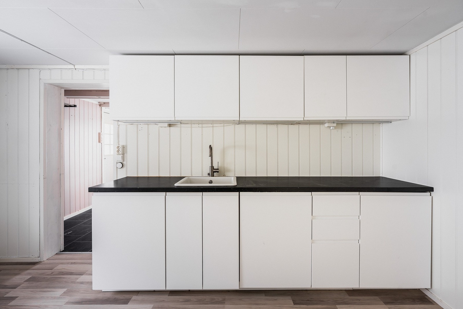 Skapplassen er meget god, og innredningen har hvite, glatte fronter, nedfelt oppvaskkum og laminert benkeplate i sort design. Galleribilde