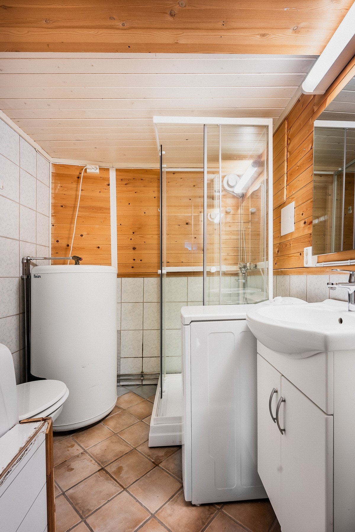 Badet er innredet med gulvfliser, kombinert med fliser og trepanel på veggene. Opplegg for vaskemaskin er etablert, og badet har toalett, gulvvarme og dusjkabinett. Den øvrige innredningen består av et hvitt servantskap og et speil med tilhørende lys. Galleribilde