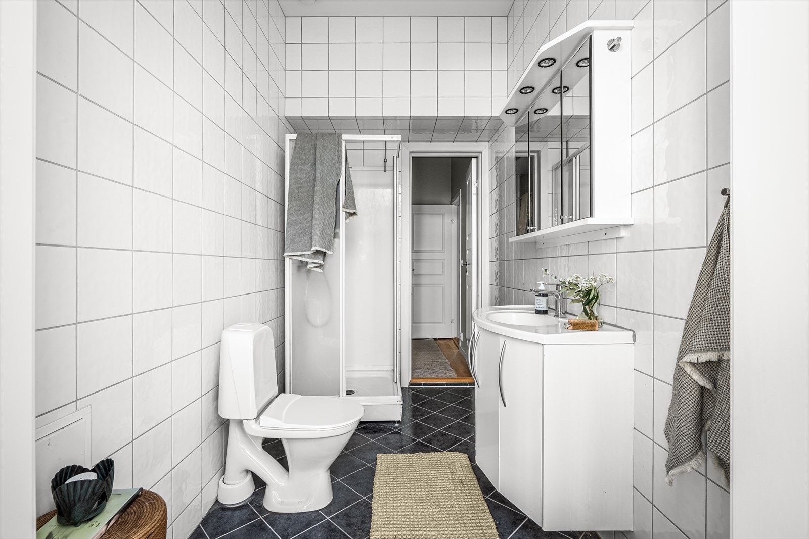 Badet er innredet med heldekkende servant med blandebatteri og speil + lys, frittstående toalett og dusjkabinett. Galleribilde