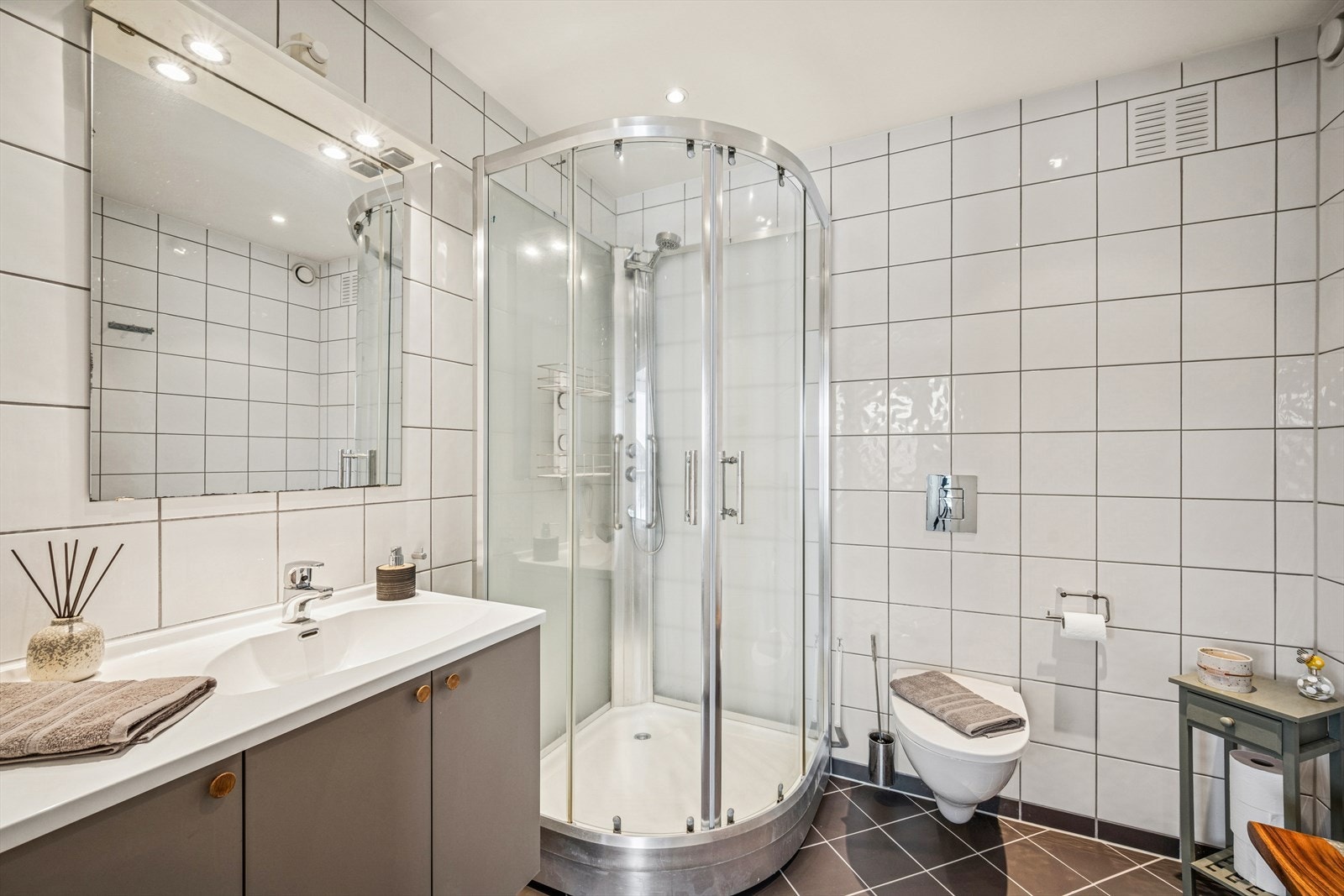 Det er 2 pene flislagte bad. Det er dusjkabinett og servant med underskap på badet i 2. etasje. Galleribilde