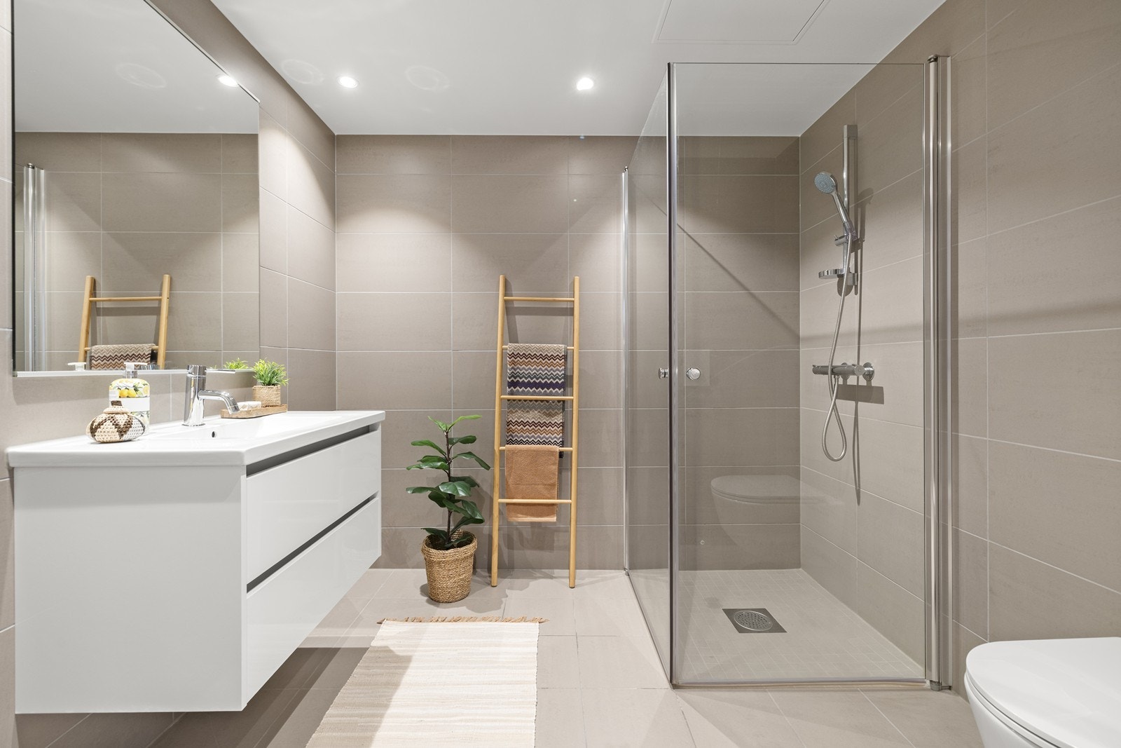 Badet er helfliset med en romslig dusjnisje med glassdører og varme i gulvet. Galleribilde