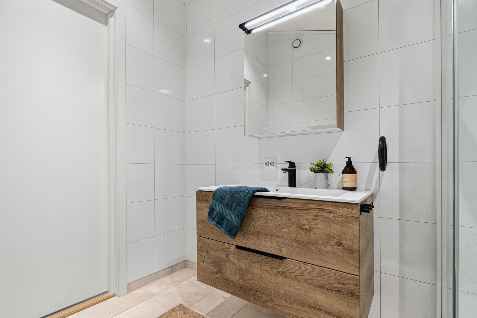 Innredet med dusjkabinett, veggmontert toalett og heldekkende servant i baderomsinnredning Galleribilde